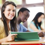 Side view of teenage pupils sitting in the classroom and writing in their notebooks. Caucasian young woman wearing yellow t-shirt is looking at the camera.[url=http://www.istockphoto.com/search/lightbox/9786738][img]http://dl.dropbox.com/u/40117171/group.jpg[/img][/url]
